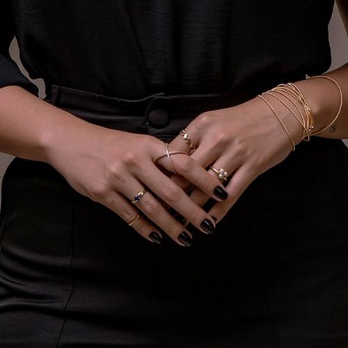 Detalhe das mãos da Dra. Mahara com joias douradas